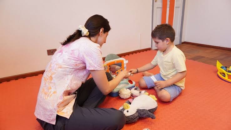Terapeuta juega con un niño sobre un piso de goma
