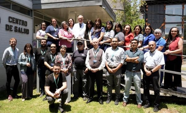 Equipo de funcionarios de salud posando frente a un centro de salud