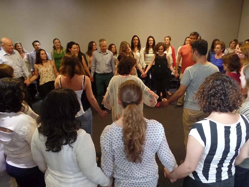 Grupo de personas tomadas de la mano en círculo durante una actividad de autocuidado