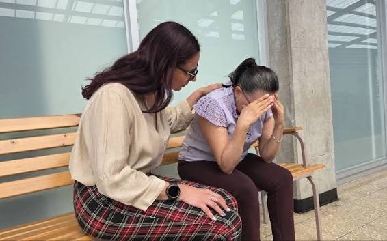 Mujer consuela a otra que llora sentada en una banca