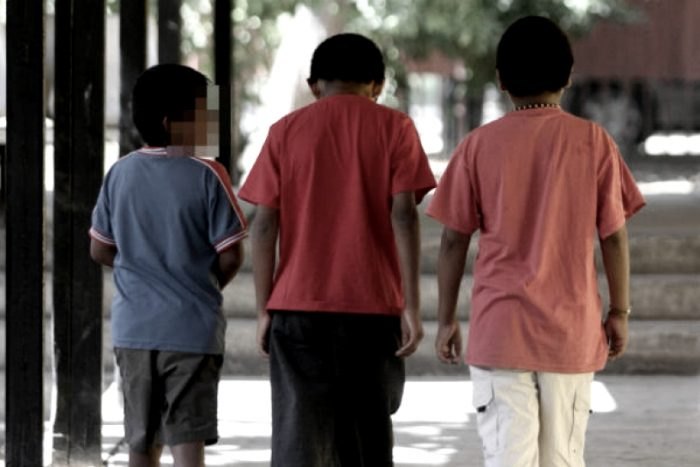 Tres niños de espaldas caminan juntos por un espacio al aire libre